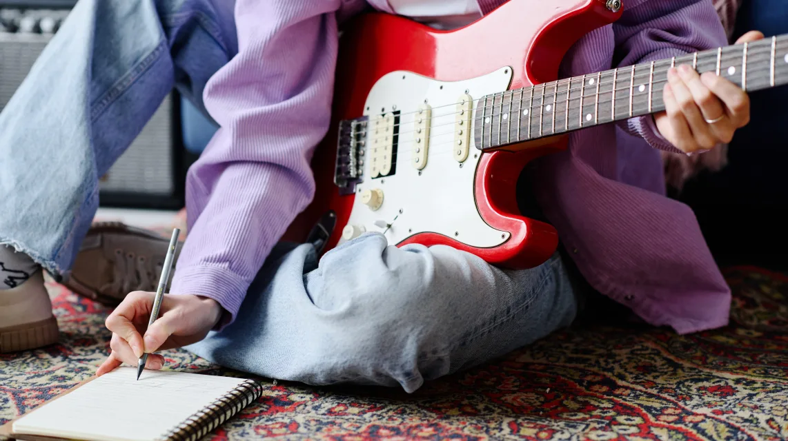 Songwriter playing guitar while writing a new song