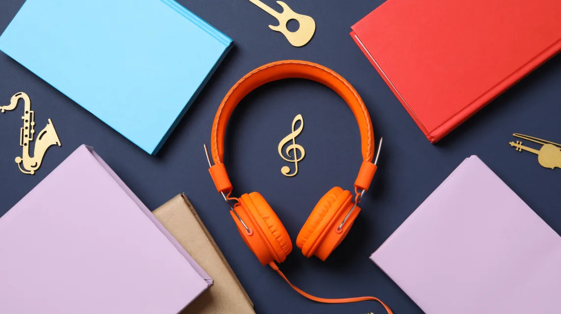 Flat lay of headphones, coloured covers and gold instrument shapes on a dark background