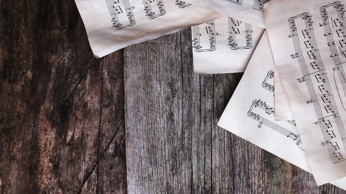 Handwritten music sheets spread across a worn wooden table