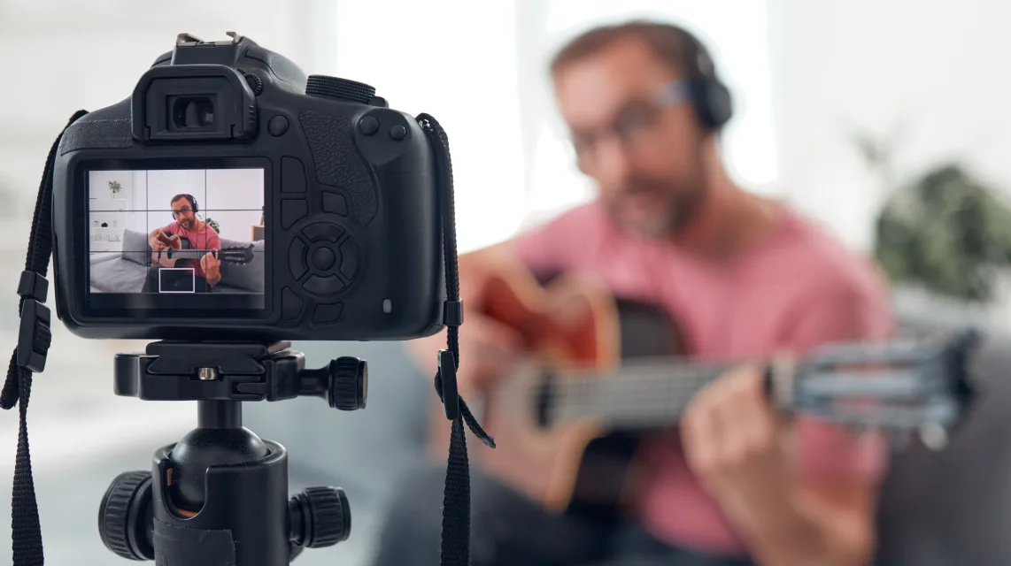 Musician filming himself playing guitar at home