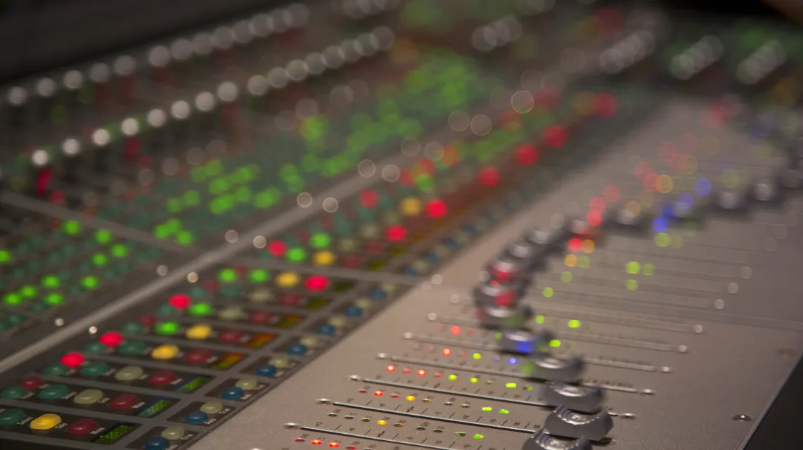 Close-up of mixing console faders and level meters