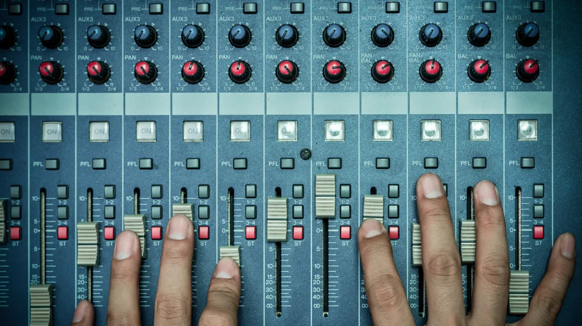 Hands adjusting equalisation controls on an audio mixer, seen from above